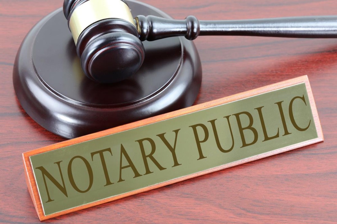 A notary public desk sign beside a gavel on a wooden desk