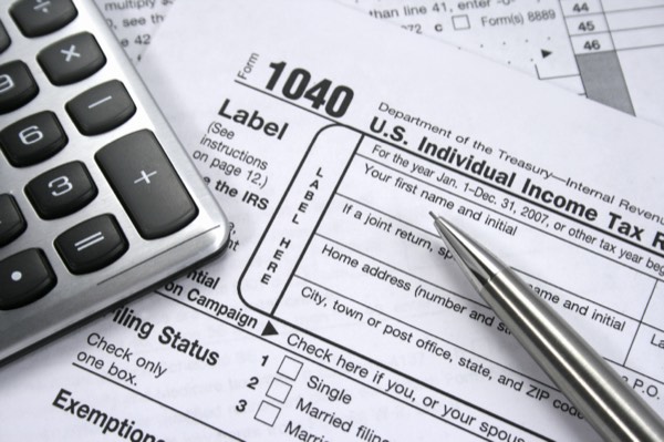 A 1040 personal income tax form with a calculator and pen